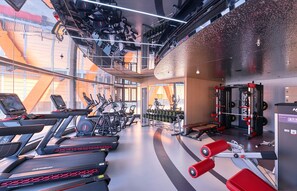 A modern gym with treadmills, elliptical machines, weightlifting equipment, and a mirrored wall. - Chongqing Hongyadong Mehood Elegant (Chongqing)