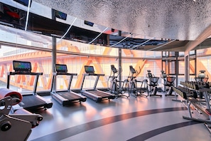 Un gimnasio moderno con cintas de correr, elípticas y bancos de pesas.