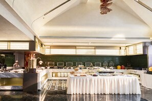A spacious hotel dining area with a high ceiling, a central buffet table, and a chef preparing food. - Chongqing Hongyadong Mehood Elegant (Chongqing)