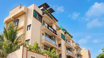 A multi-story hotel building with balconies, a sign indicating it is a hotel, and a clear blue sky in the background.