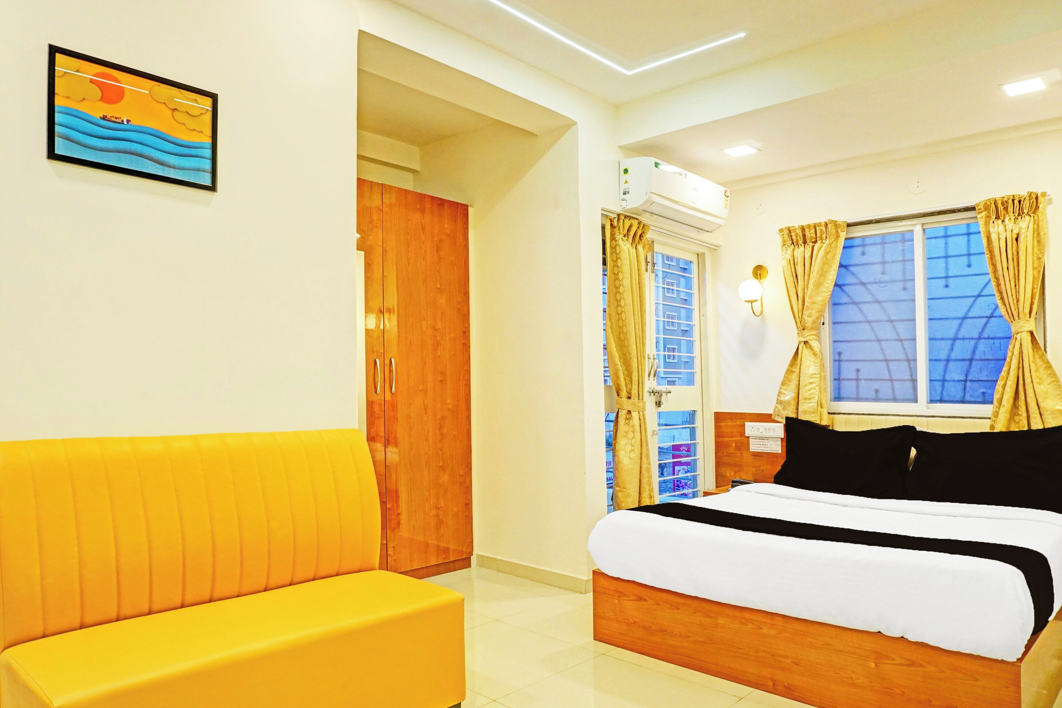 A hotel room with a bed, a sofa, a window with curtains, and a painting on the wall.