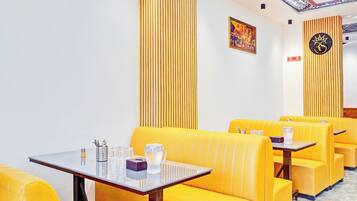 A restaurant interior with yellow booths, a table with cutlery, glasses, and a teapot.