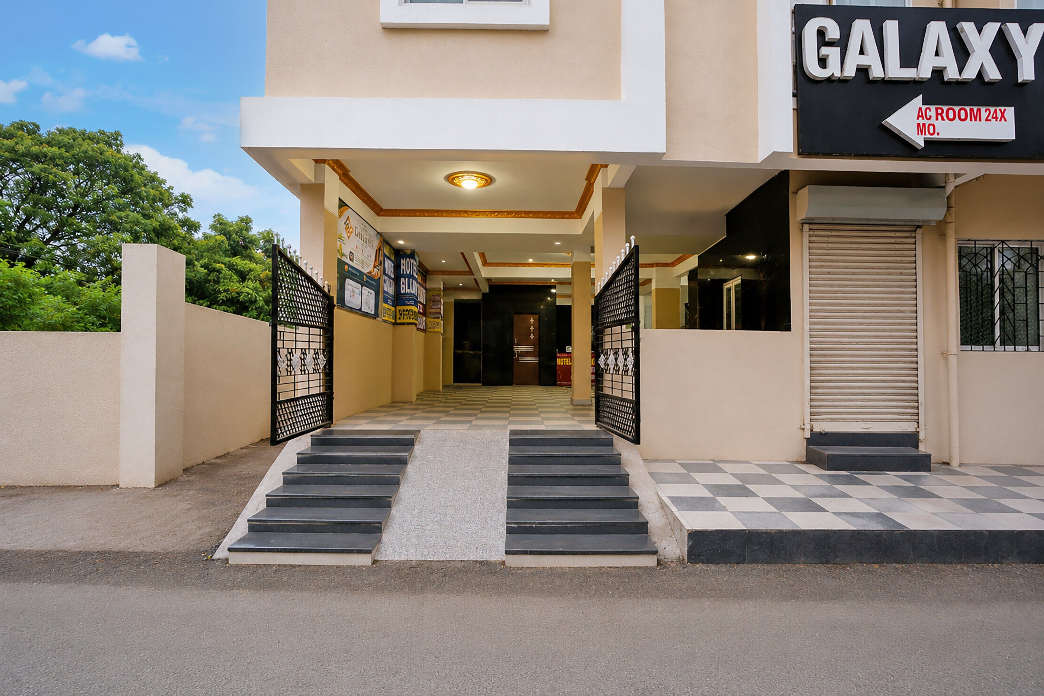 L’entrée d’un hôtel, avec une enseigne indiquant « GALAXY » et une flèche pointant vers « CHAMBRE CLIMATISÉE 24X MO. »