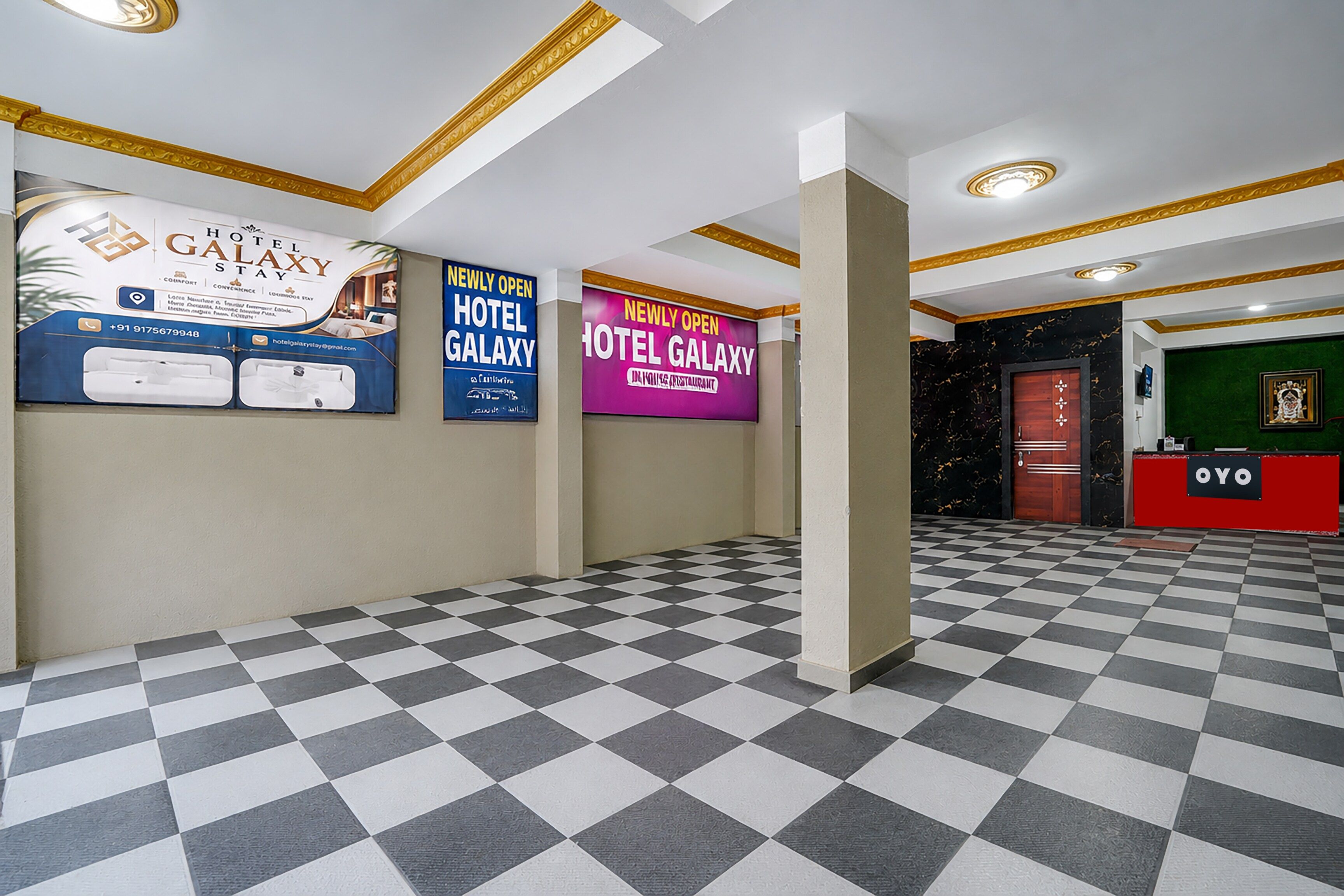 Un hall d’hôtel avec un sol à carreaux, un comptoir d’accueil et de nombreux panneaux publicitaires présentant l’hôtel et ses services.