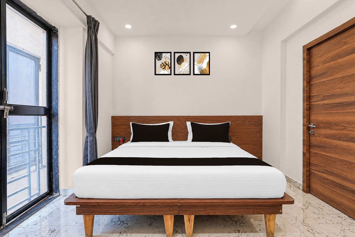 Ein modernes Schlafzimmer mit einem Bettgestell aus Holz, einem großen Fenster und drei gerahmten Kunstwerken an der Wand.