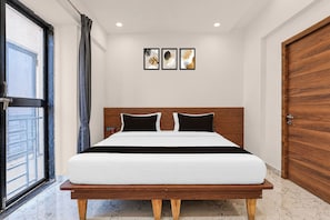 Ein modernes Schlafzimmer mit einem Bettgestell aus Holz, einem großen Fenster und drei gerahmten Kunstwerken an der Wand.