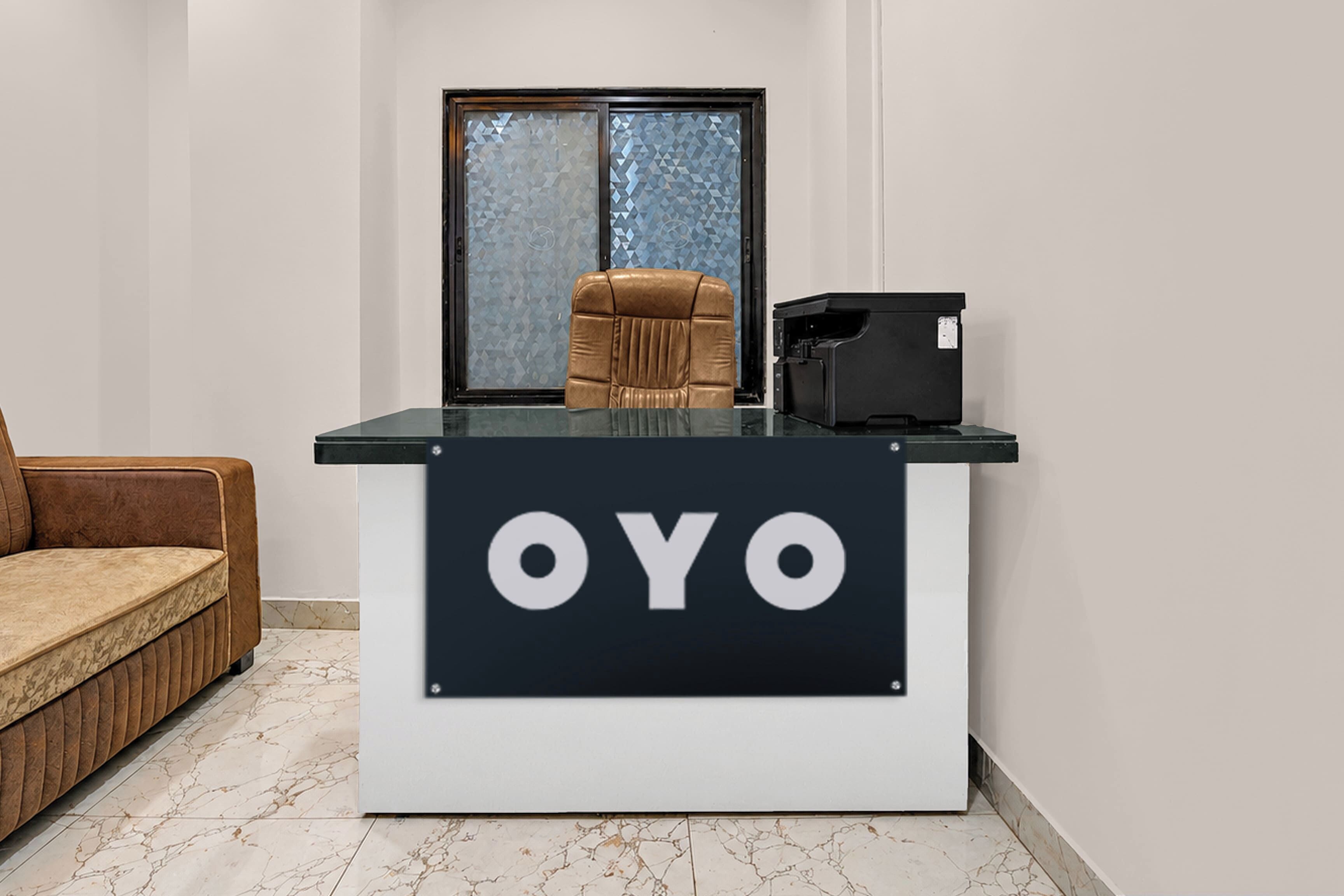 A reception desk with 'OYO' branding, a brown leather chair, and a window with a geometric pattern.