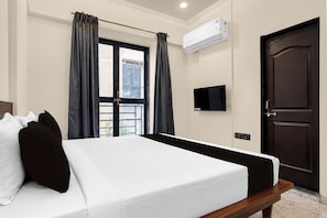 Ein Hotelzimmer mit Bett, Fernseher, Klimaanlage und einer Tür.
