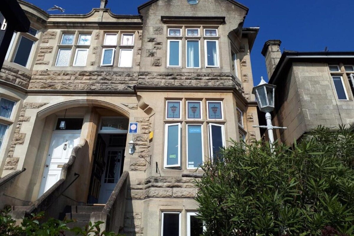A stone building with multiple windows, a central entrance, and a staircase leading to the entrance.