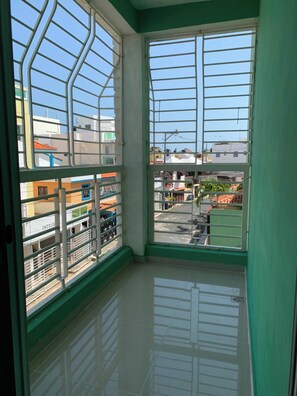 Quarto com uma grande janela, piso de azulejos e vista para edifícios.