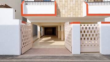Entrada de um edifício com uma entrada de automóveis protegida e um corredor coberto.