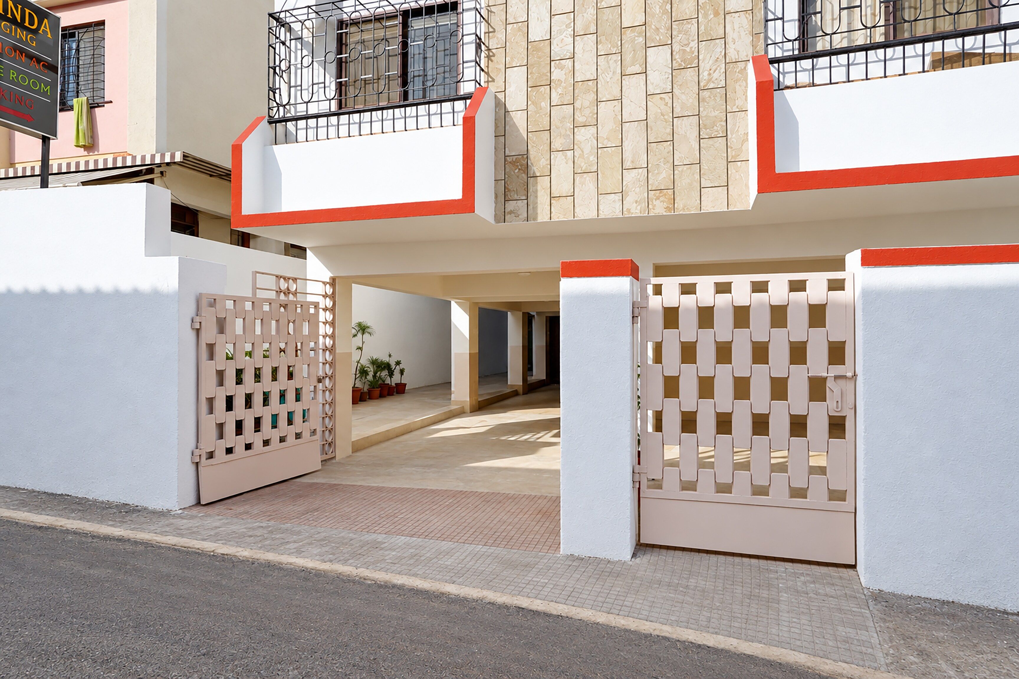 Entrada fechada por grades para um edifício residencial, com fachada revestida de azulejos e uma varanda com guarda-corpo de metal.