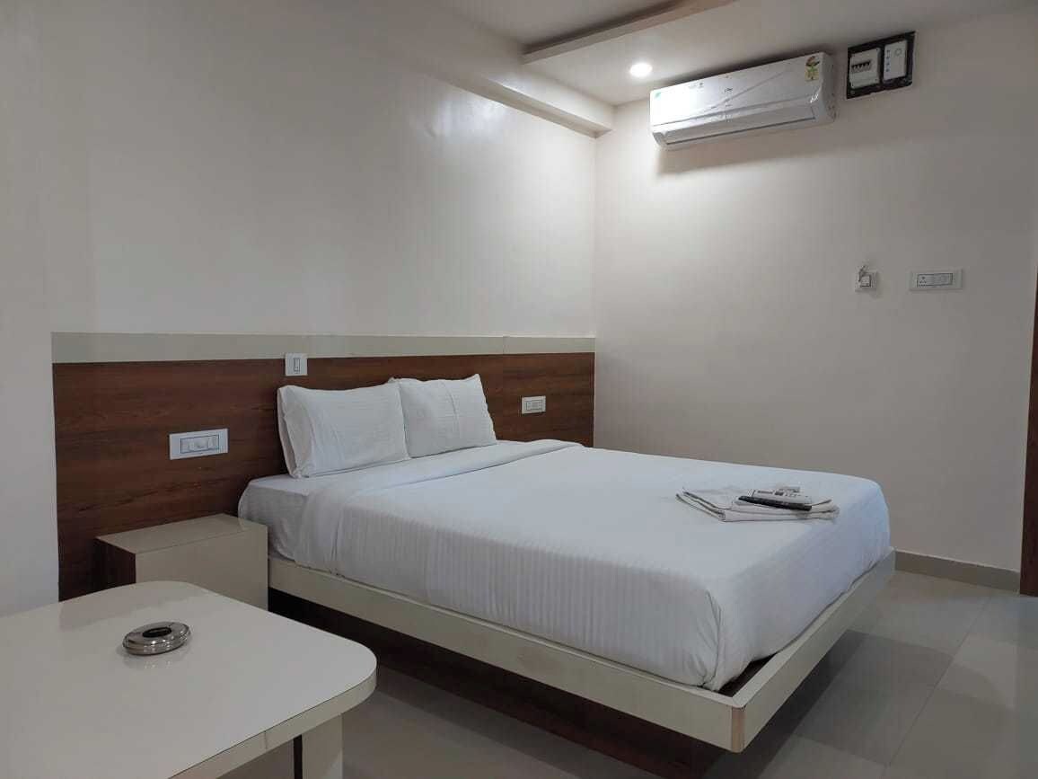 Una habitación de hotel con una cama individual, una mesita de noche y un escritorio pequeño.