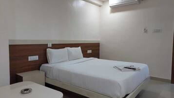 Una habitación de hotel con una cama individual, una mesita de noche y un escritorio pequeño.