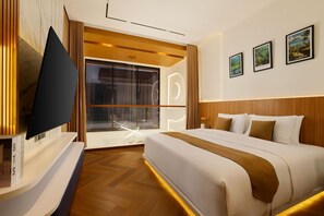 Et moderne hotelværelse med en stor seng, et fladskærms-tv, et stort vindue med gardiner og indrammet kunst på væggen.