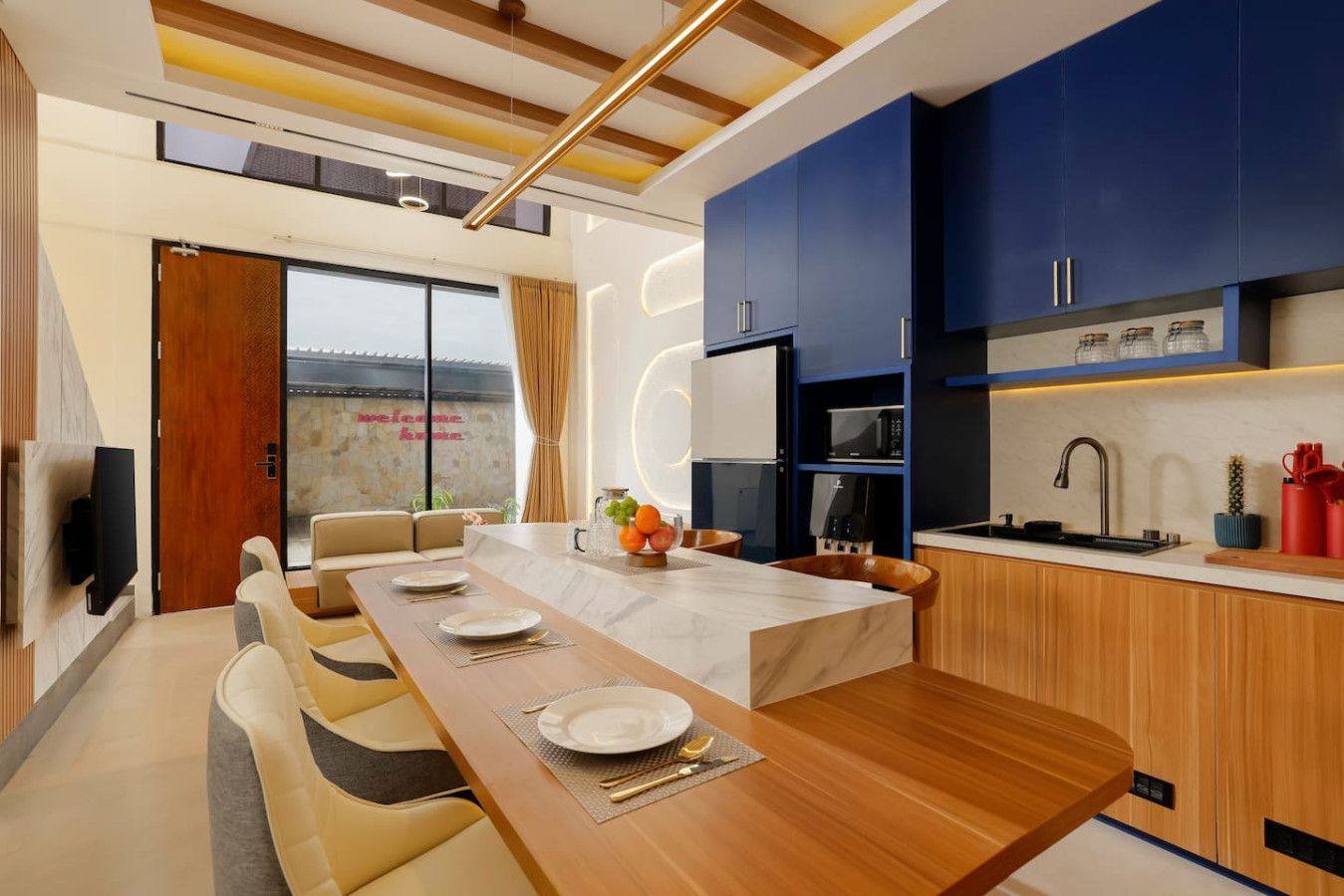A modern kitchen with blue cabinets, a wooden dining table set for four, and a built-in oven.