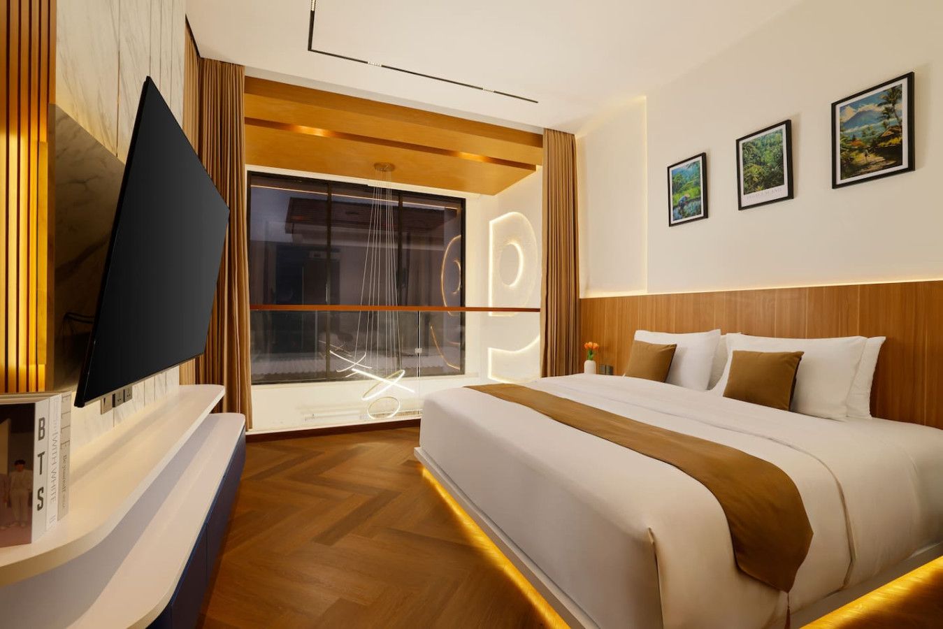 A hotel room with a large bed, a flat-screen TV, a window with curtains, and artwork on the wall.