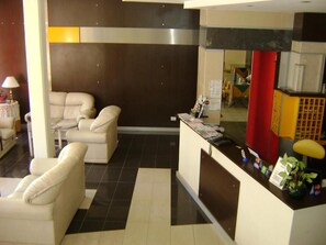 A reception area with a reception desk, a sofa, and a chair. - Hotel Brisolei (San Bernardo del Tuyú)