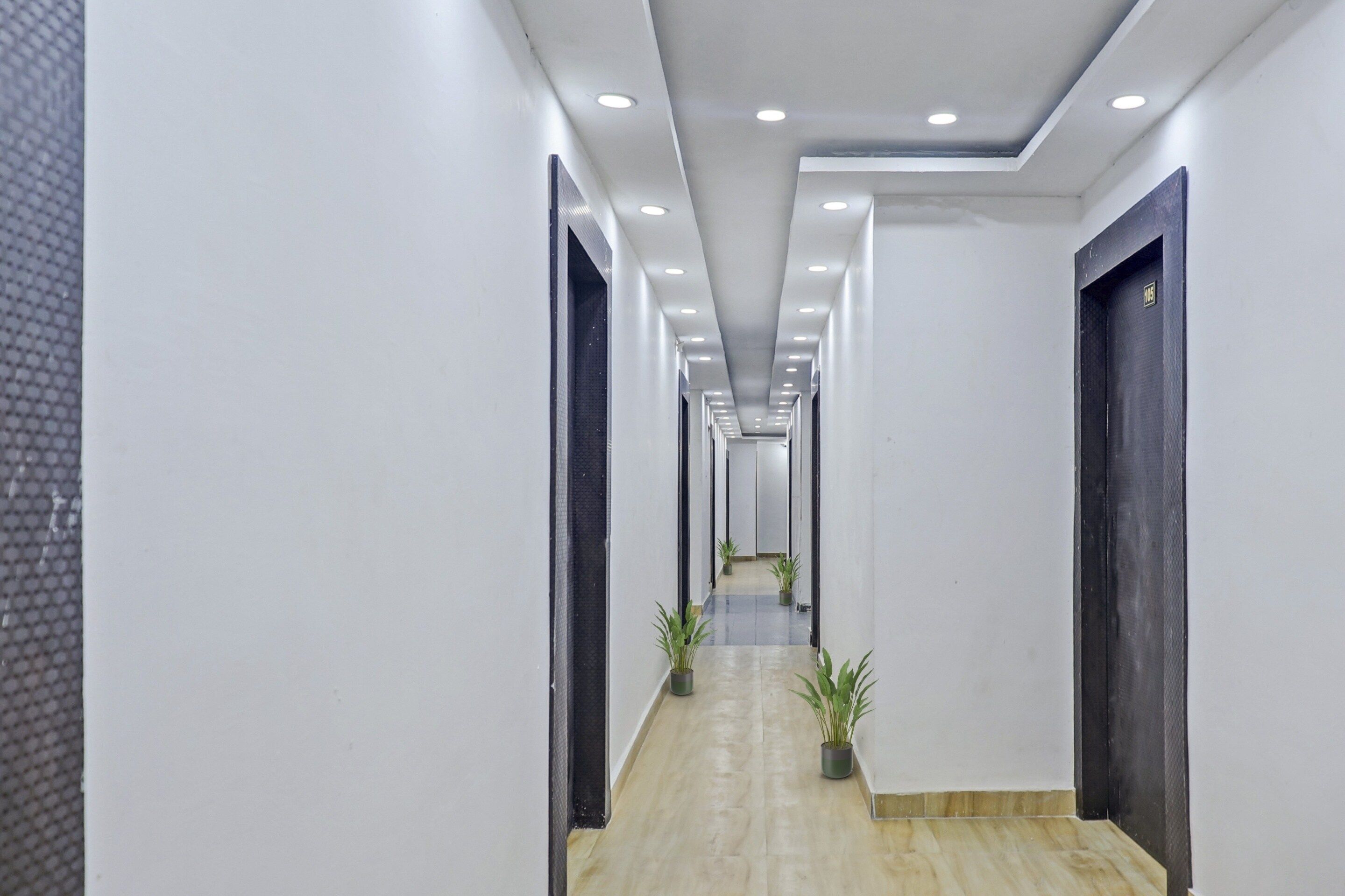 A modern hallway with a light-colored floor, white walls, and a series of doors on both sides.