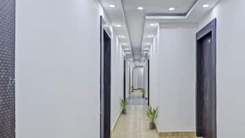 A modern hallway with a light-colored floor, white walls, and a series of doors on both sides.
