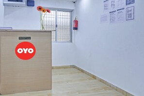 Un área de recepción con un mostrador de madera identificado con las etiquetas 'RECEPTION' y 'OYO'.