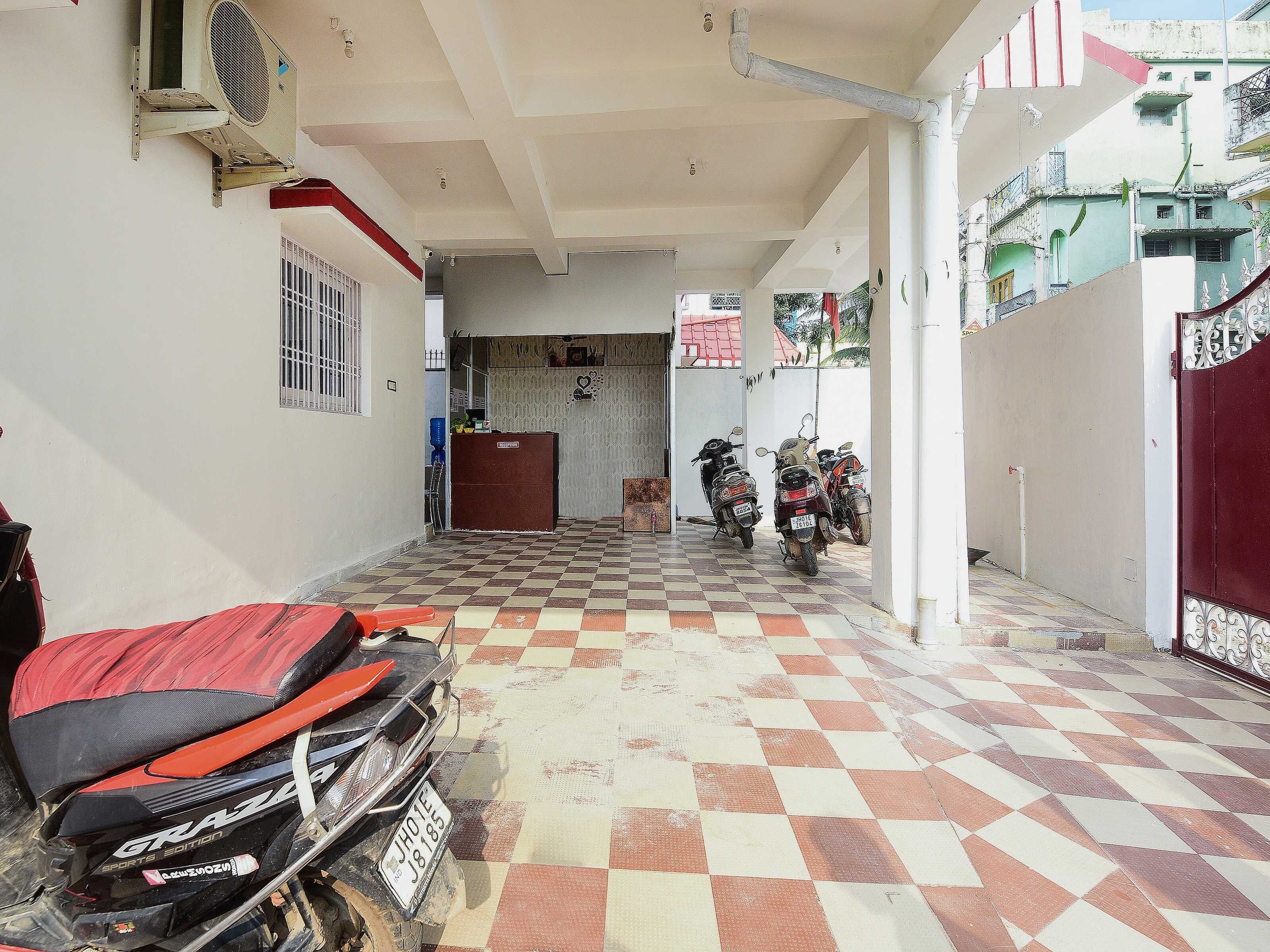 Un espacio exterior cubierto con suelo a cuadros, una reja roja y motocicletas estacionadas.