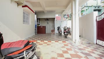 Un espacio exterior cubierto con suelo a cuadros, una reja roja y motocicletas estacionadas.