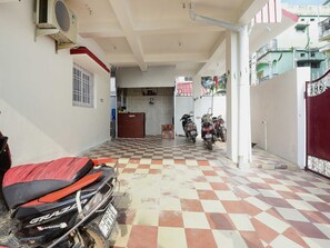 Un espacio exterior cubierto con suelo a cuadros, una reja roja y motocicletas estacionadas.
