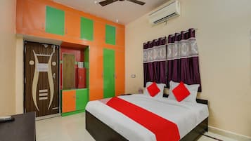 Una habitación de hotel con cama, escritorio, armario y ventilador de techo.