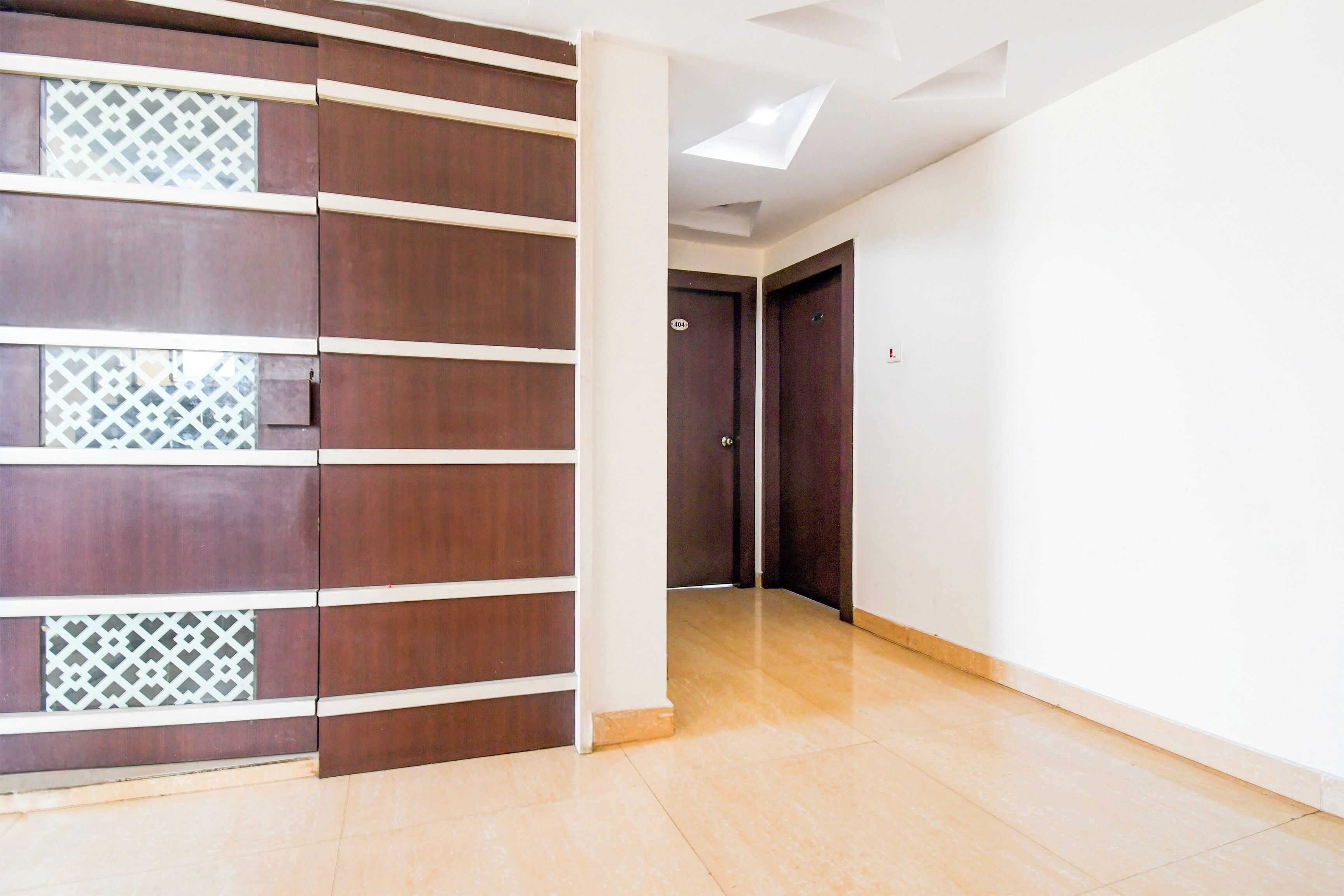 A hallway with a wooden partition, a tiled floor, and a door with a number plate.