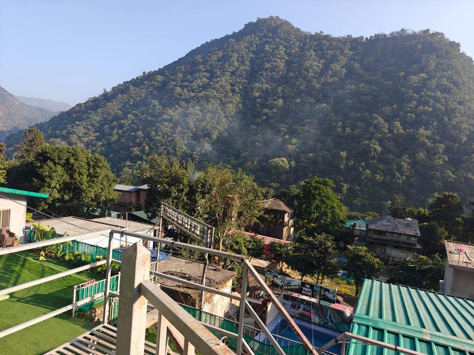 A mountainous landscape with a view of a residential area, including houses and a green-roofed building.