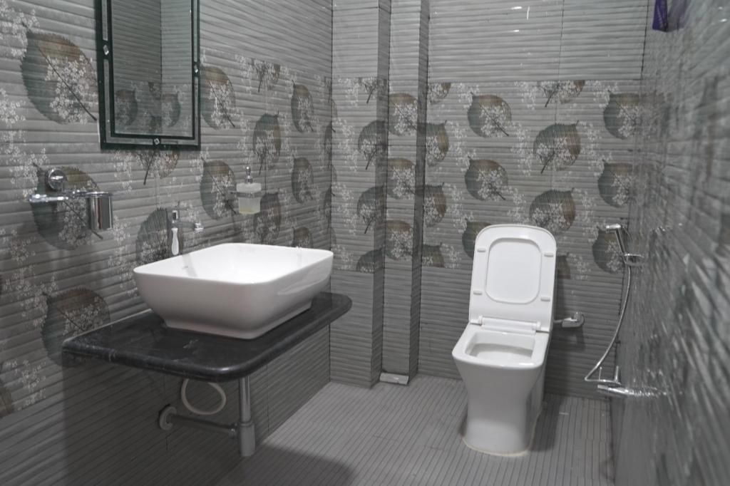 Een badkamer met een wit wastafel, toilet en spiegel.