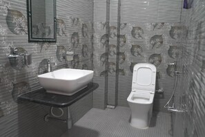 Une salle de bain avec un lavabo blanc, des toilettes et un miroir.