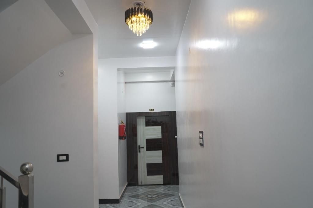 Un couloir avec un lustre, une porte dotée d’une poignée et un extincteur fixé au mur.