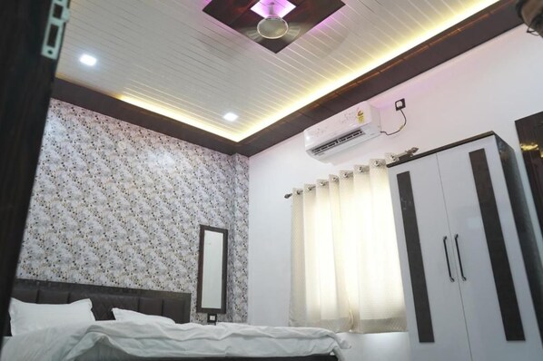 A bedroom with a bed, a wardrobe, a mirror, and an air conditioning unit. - Swastik Stay Inn  (Anmol Nagar ,Sarnath ,Varanasi)