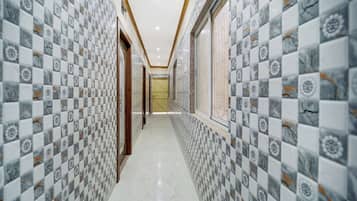 A corridor with patterned tiles on the walls and a tiled floor, leading to a door at the end.