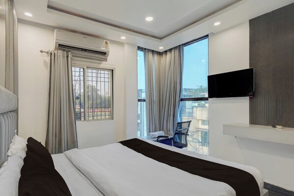 A hotel room with a bed, a flat-screen TV mounted on the wall, a window with curtains, and a view of the outside. - Hotel O Aksh Residency (Ranchi)