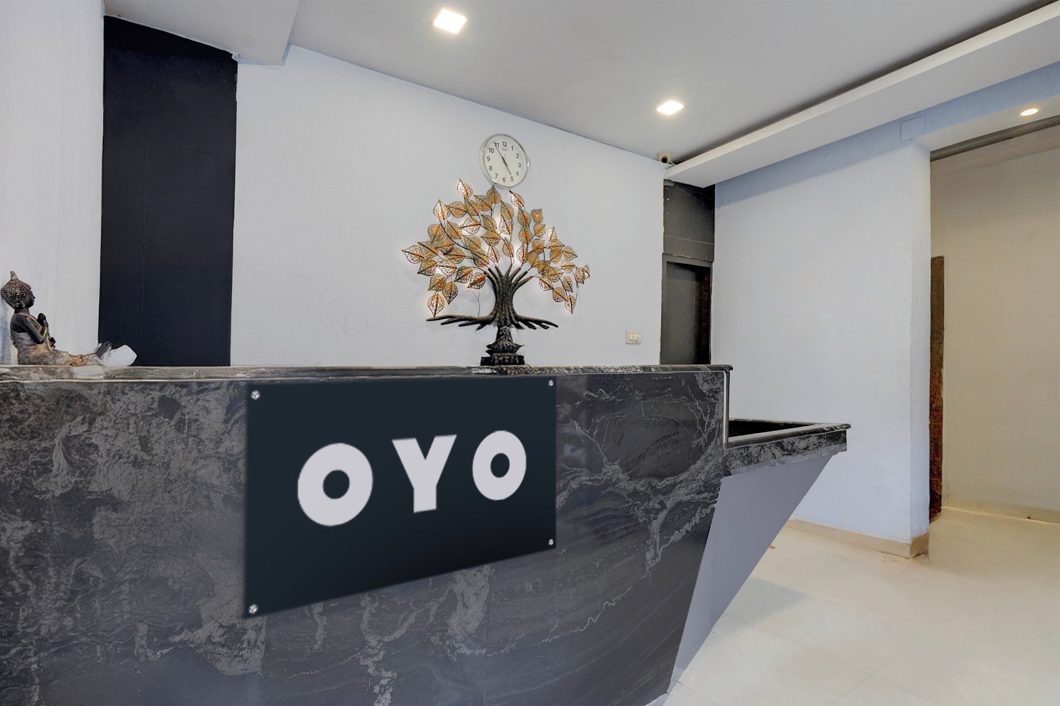 A reception desk with a sign that reads 'OYO' and a decorative tree with leaves.