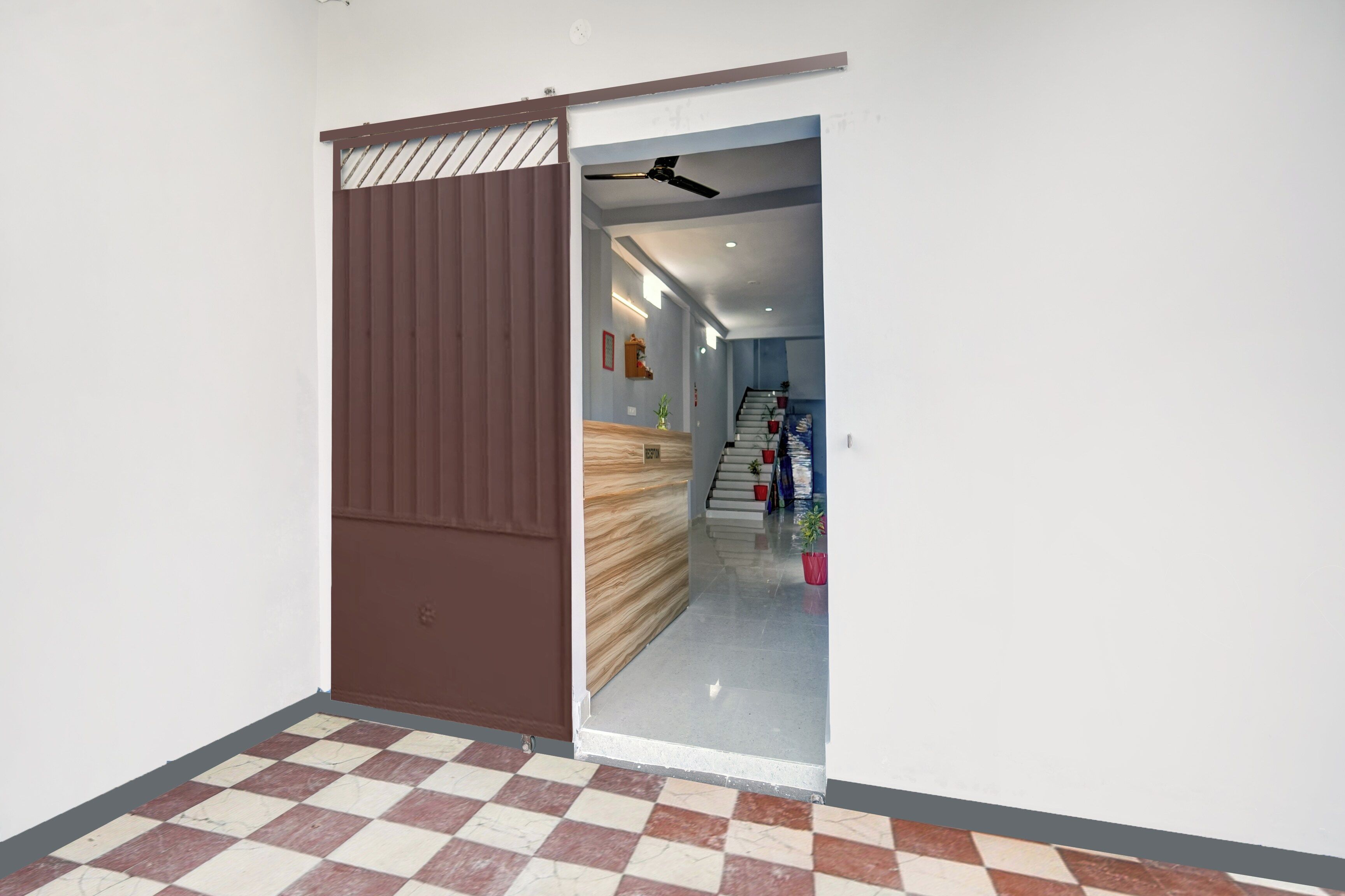 A hallway with a checkered floor, a sliding door, and a staircase leading to another level.
