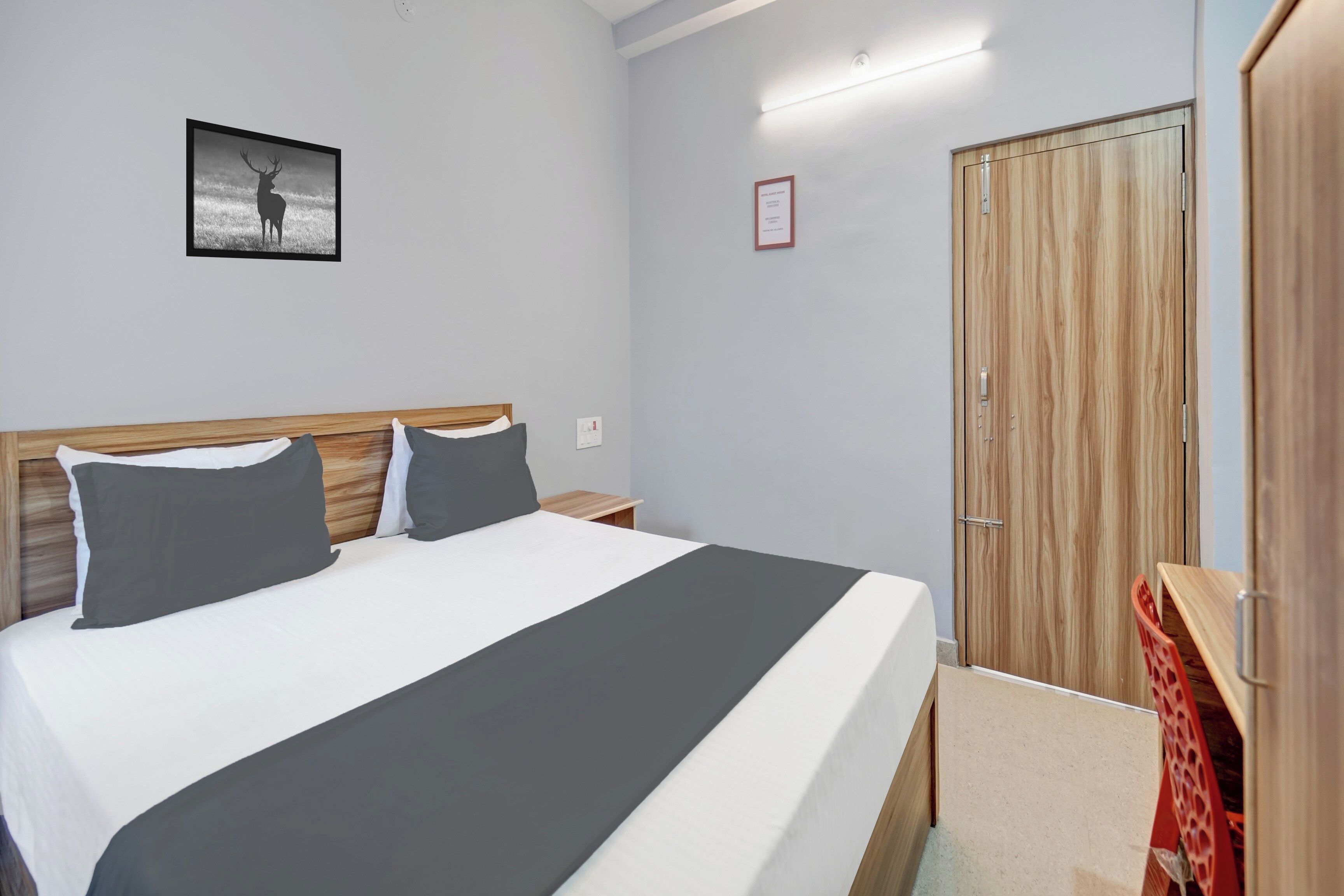 A bedroom with a bed, a nightstand, a wardrobe, and a framed picture on the wall.