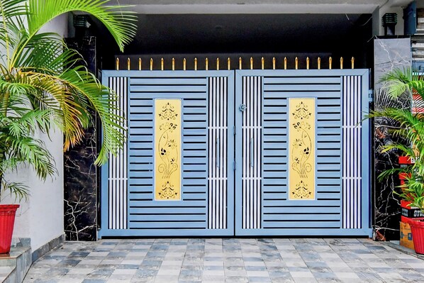Una entrada protegida por un portón con paneles decorativos y un camino de baldosas que conduce a ella.