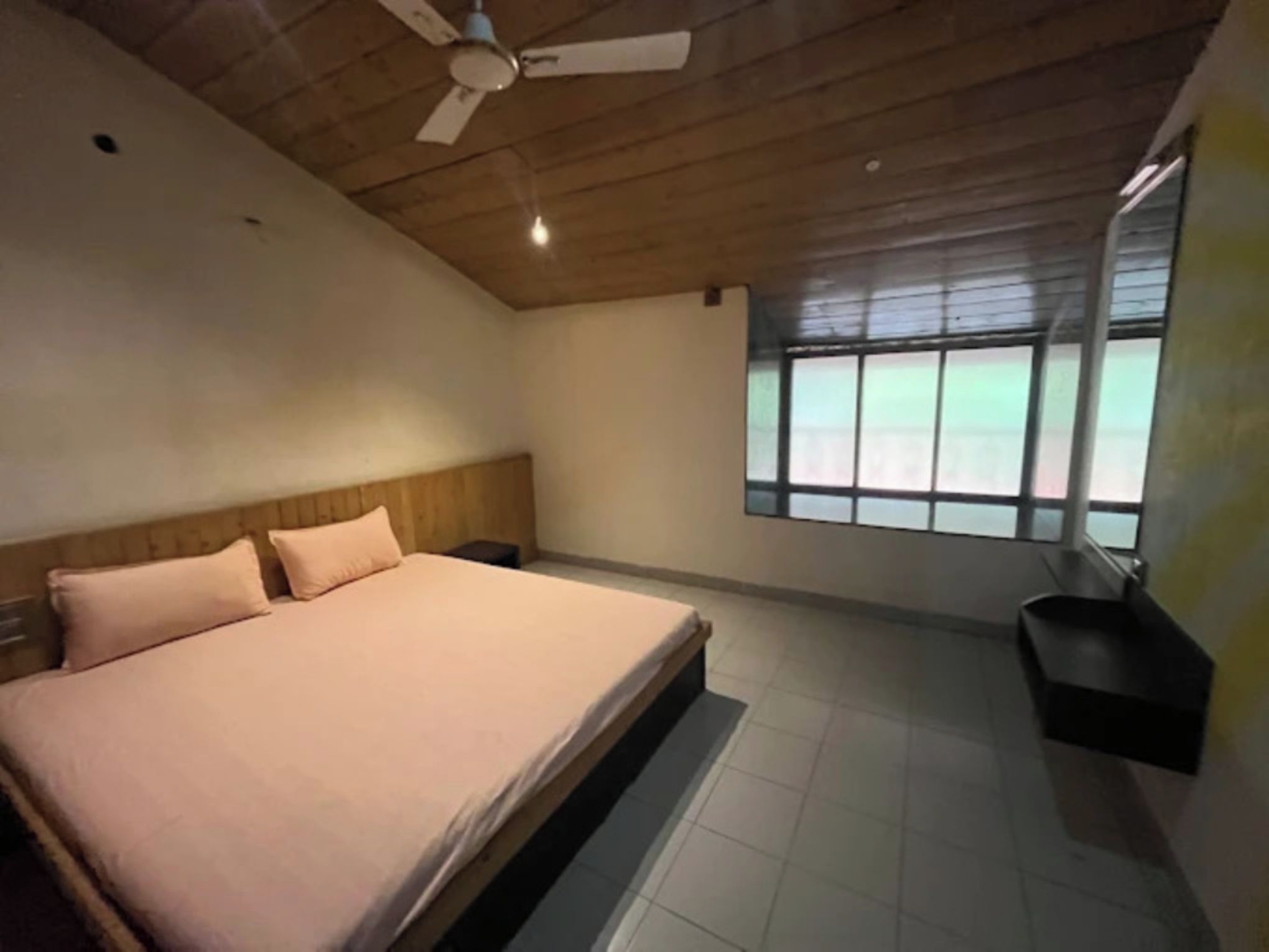 A bedroom with a bed, a ceiling fan, a window, and a built-in bench.