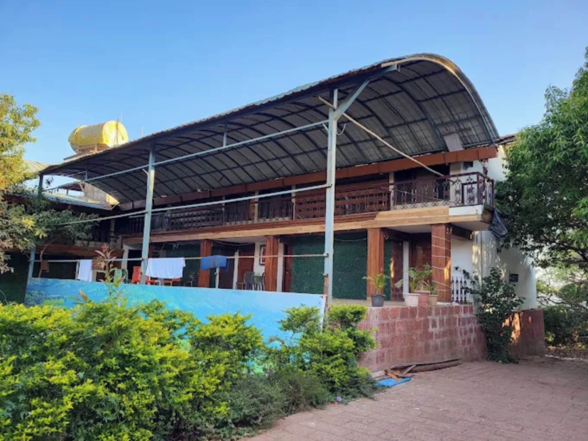 A two-story house with a curved roof, a balcony, and a fenced yard.
