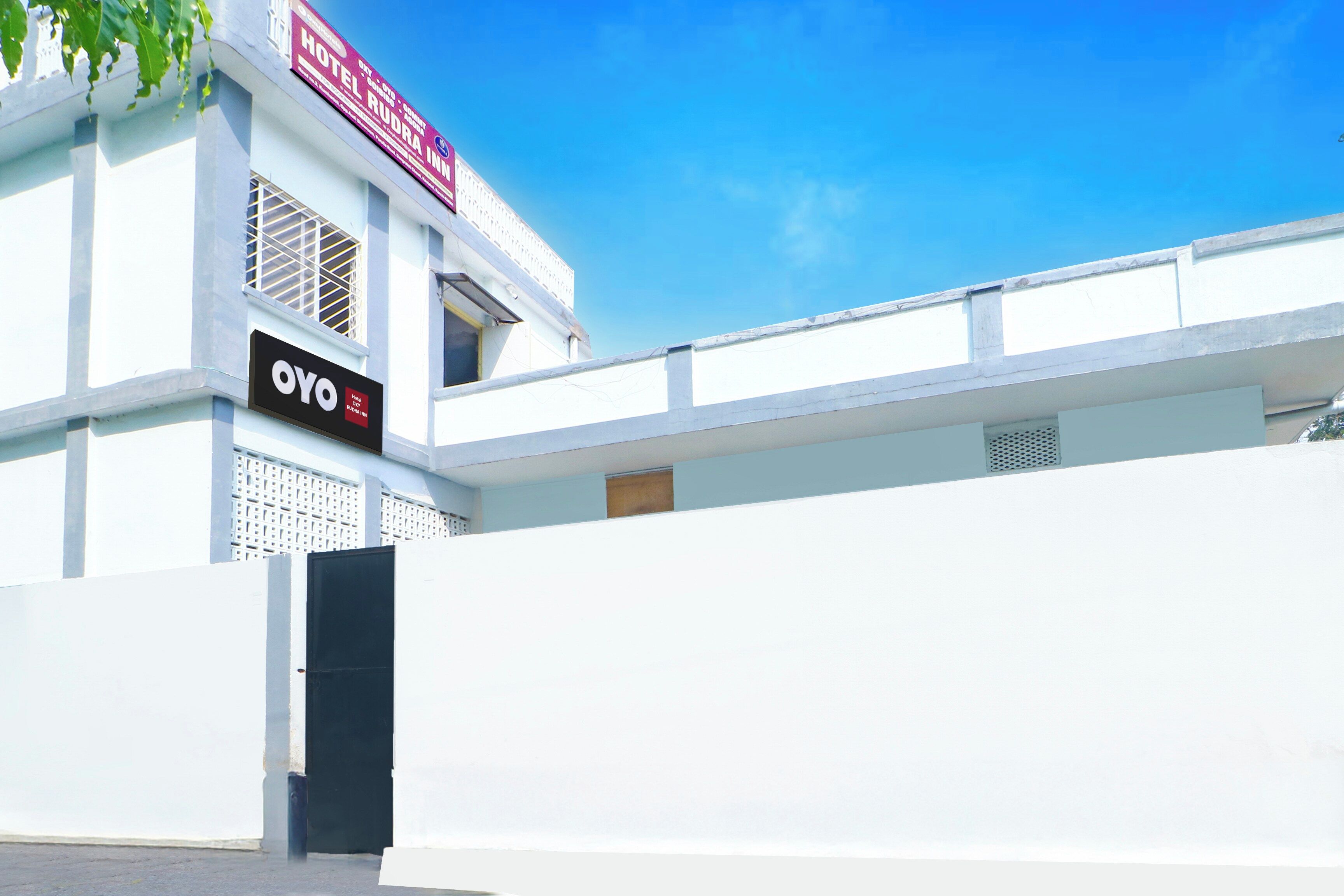 A hotel with a prominent sign for 'Hotel Rudra Inn' and a smaller sign for 'OYO Hotel City'.