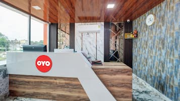 Un mostrador de recepción con un logotipo, una escalera y una pared con un reloj.