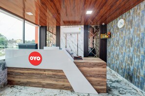 Un mostrador de recepción con un logotipo, una escalera y una pared con un reloj.