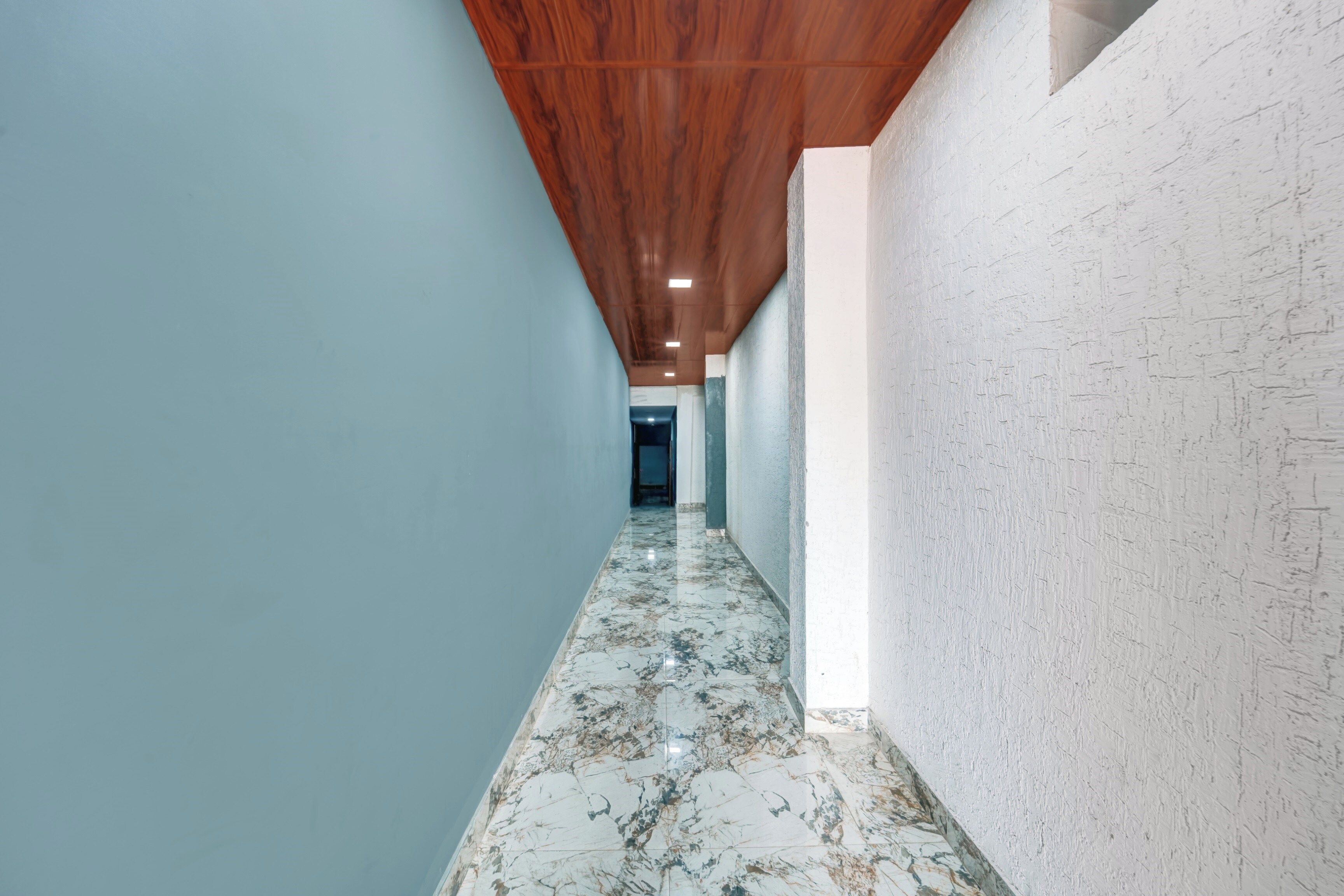 A corridor with a wooden ceiling, light blue walls, and a marble floor.