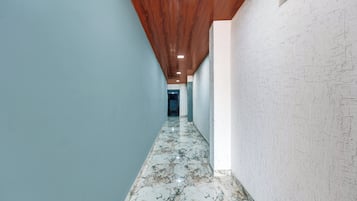 Un pasillo con techo de madera, paredes azul claro y suelo de mármol.