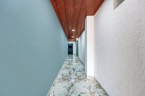 Un pasillo con techo de madera, paredes azul claro y suelo de mármol.