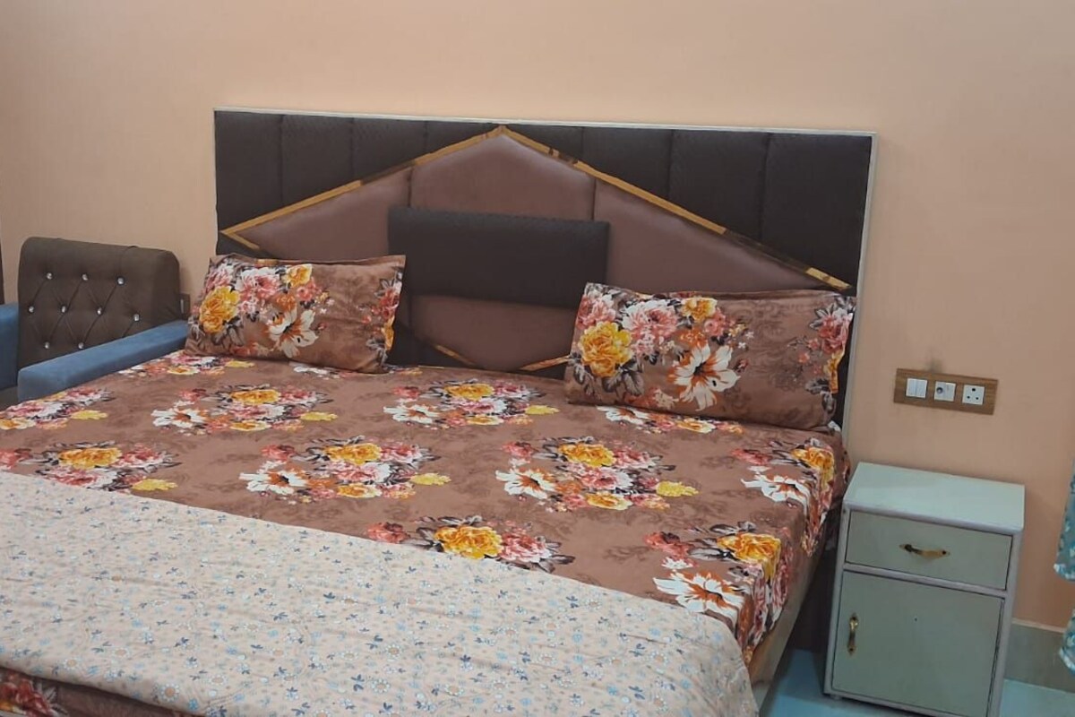 Quarto com cama, mesa de cabeceira, guarda-roupa e cortina.